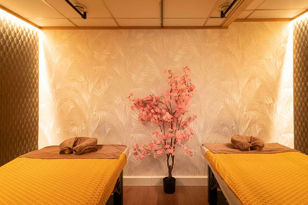Duokamer met twee massagetafels in okergeel en een roze bloesemboom
