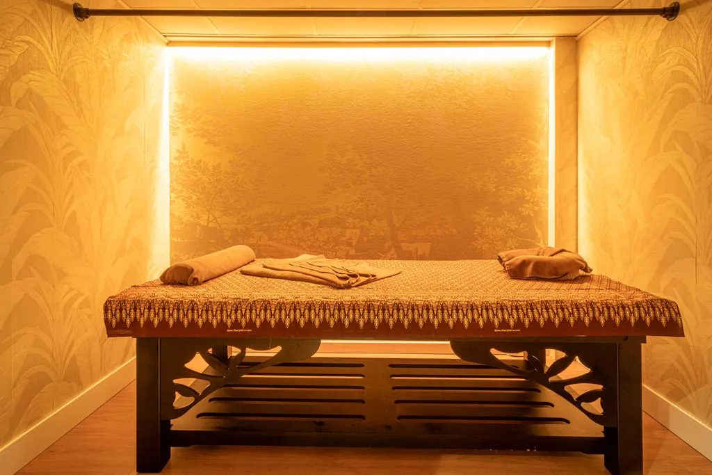 Behandelkamer met massagetafel in Thaise zijde en amberkleurige gloed