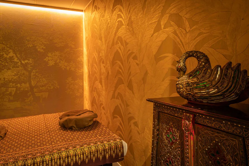 Behandelkamer met tropisch behang en een Thaise kast met zwaan